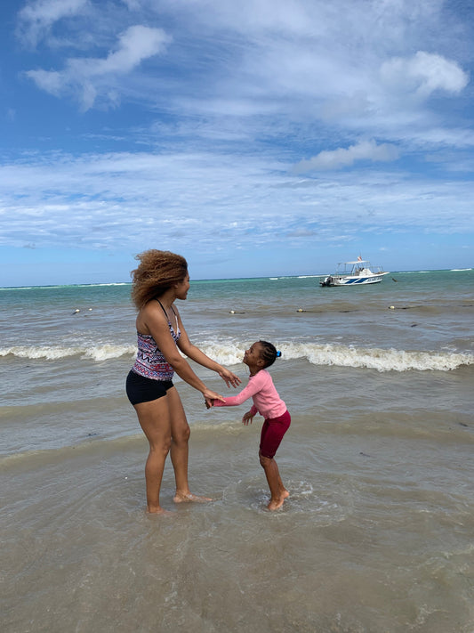 two people at the beach, with blue skies and a boat in the background