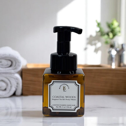 A pump bottle of Coastal Woods foaming hand soap with a label, on a bathroom countertop.
