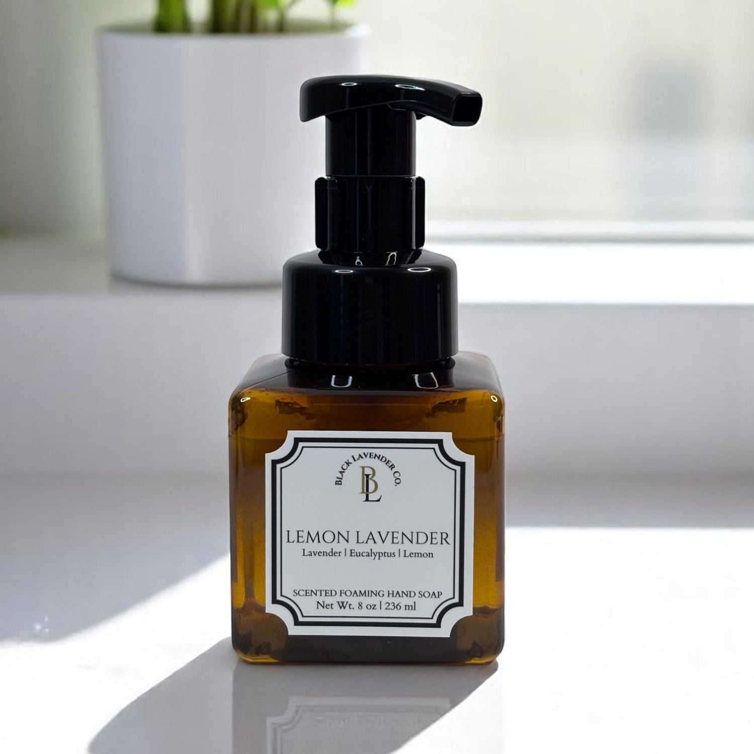 A pump bottle of Lemon Lavender scented foaming hand soap with a white label, placed on a light background.