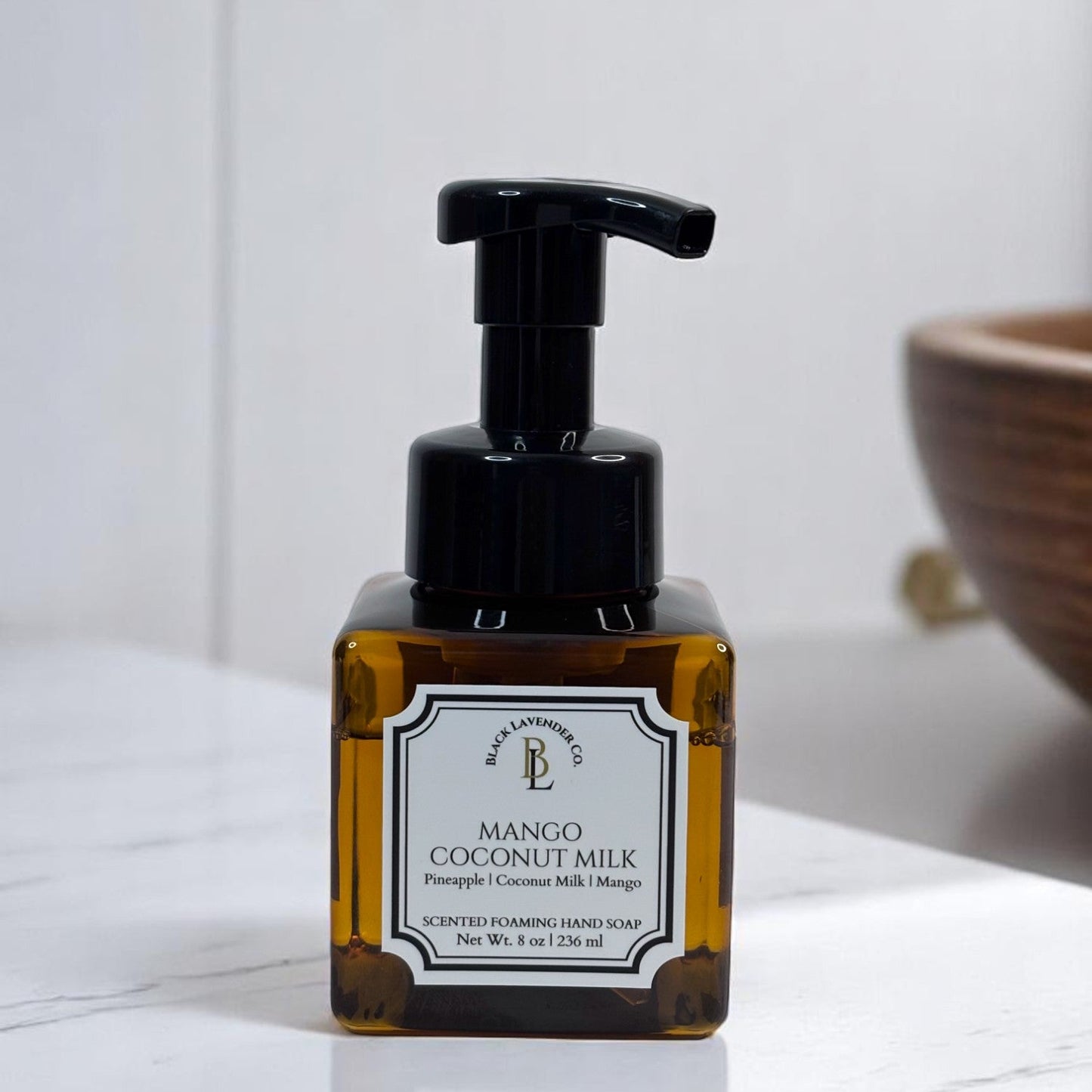 A pump bottle of Mango Coconut Milk scented foaming hand soap with a label that includes the product name and scent notes.