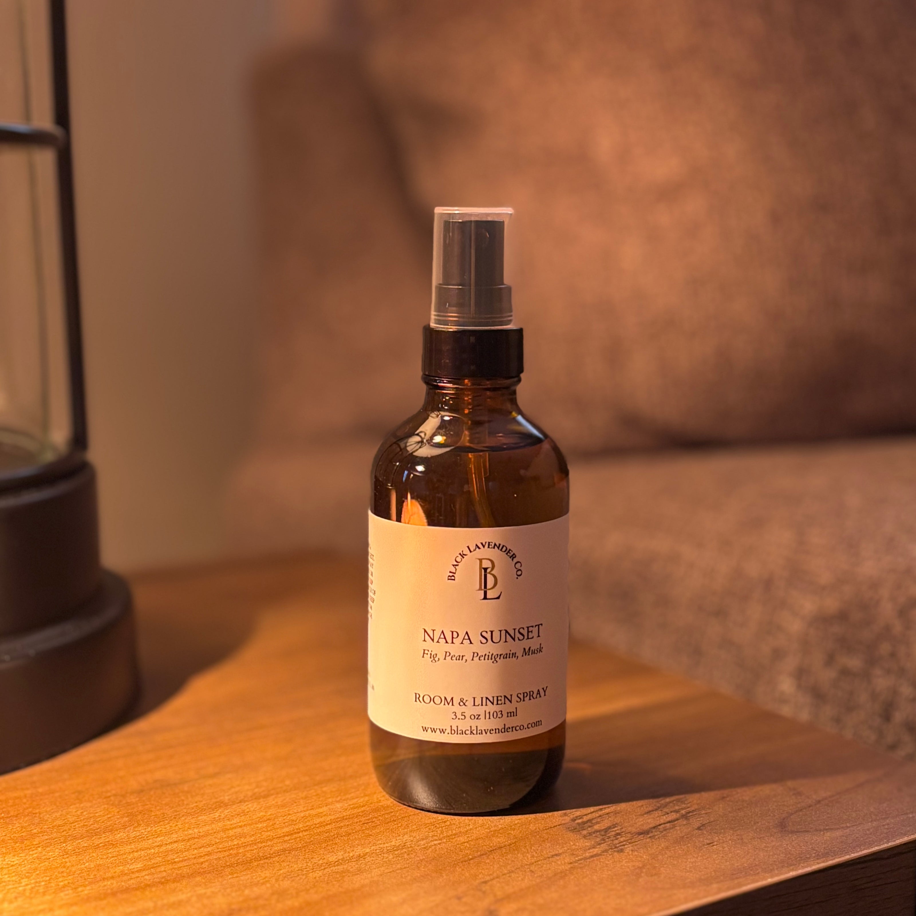 Bottle of Napa Sunset room and linen spray on a wooden surface with a lifestyle background
