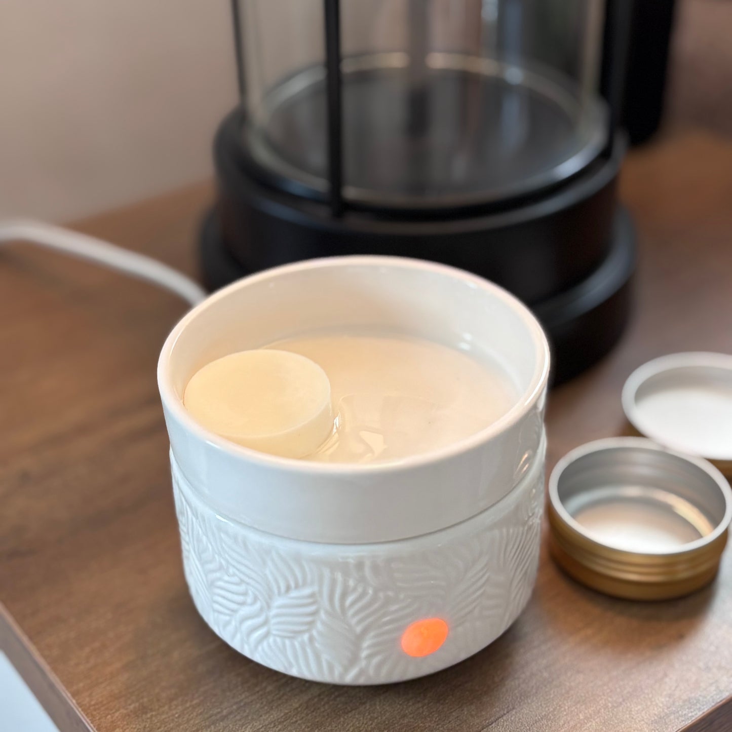 White ceramic warmer with wax sitting inside  on a wooden surface