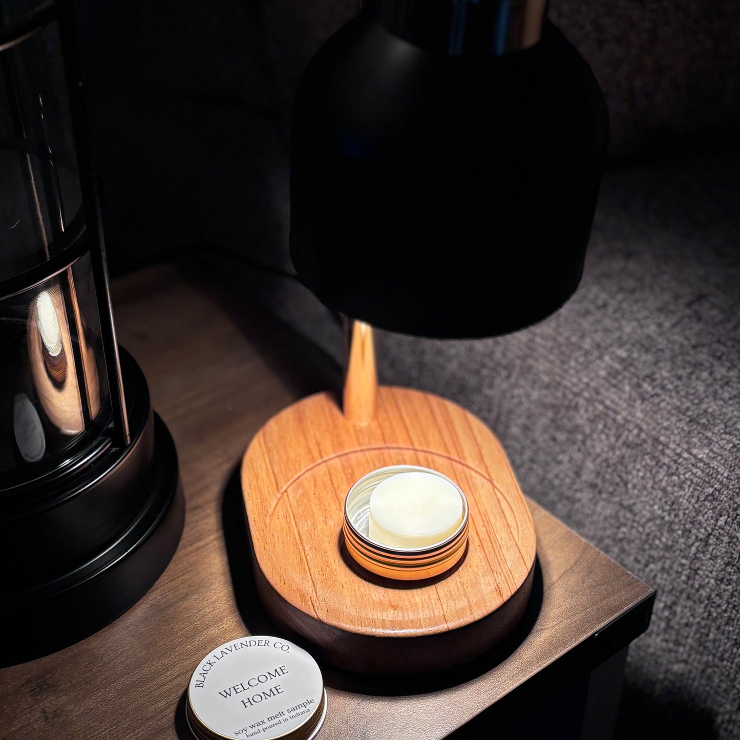 Wooden lamp with a candle on a wooden surface, surrounded by dark objects.