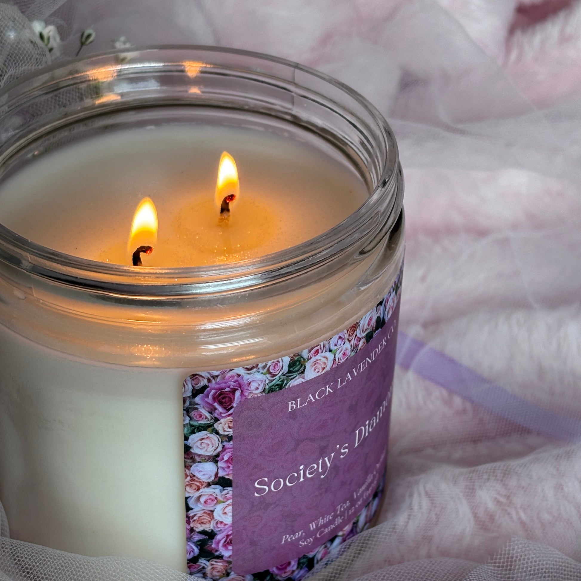 Candle with a lit wick on a soft pink fabric background