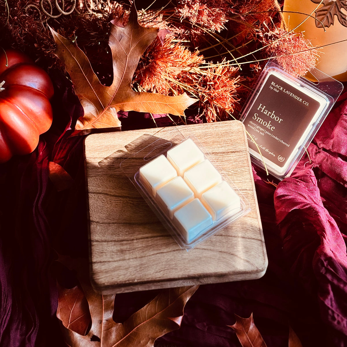 A wax melt product shown in a clear plastic clamshell package on a wooden board, with a second package labeled Harbor Smoke by Black Lavender Co. placed beside it.