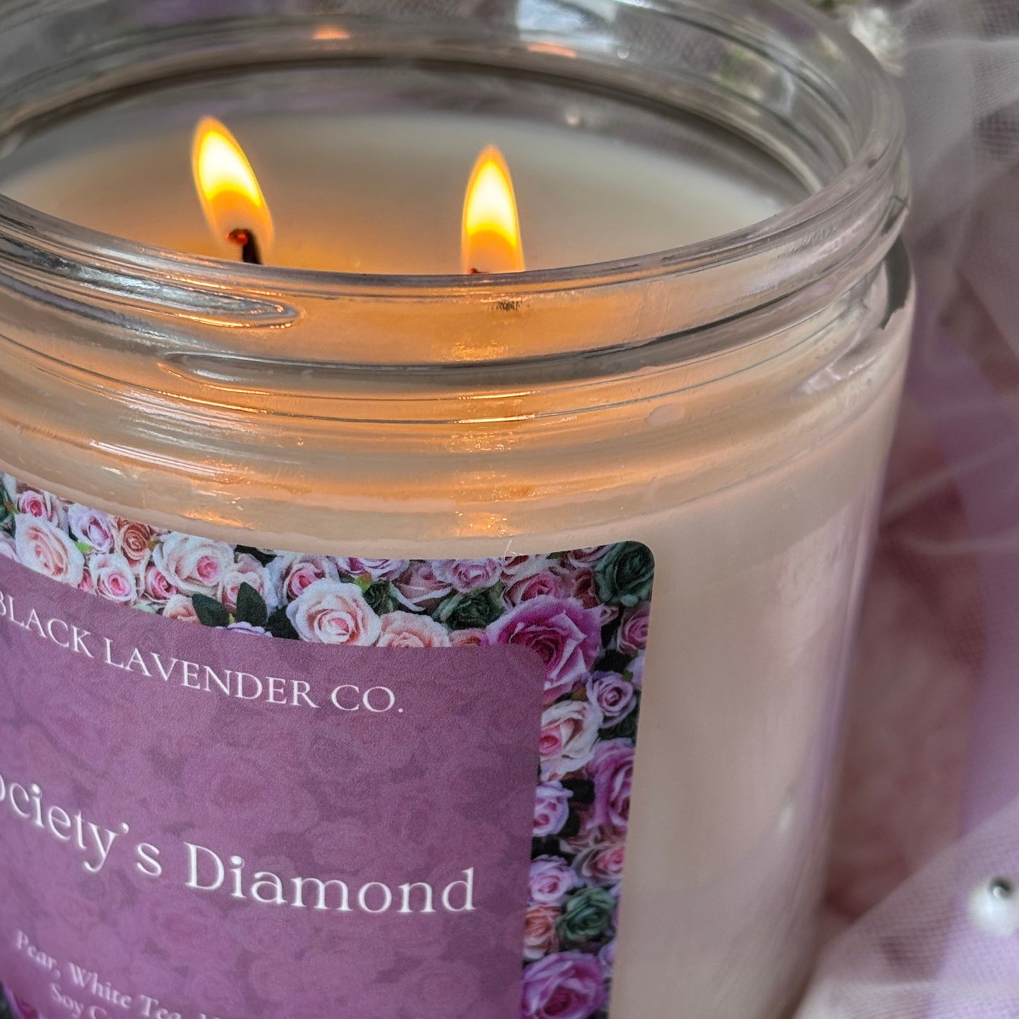 Candle in a glass jar with a decorative label on a soft fabric background